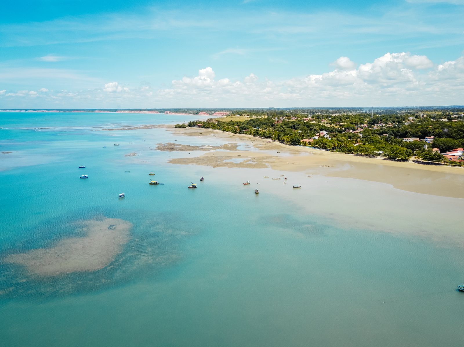 Águas cristalinas de Cumuruxatiba com barcos de pescadores